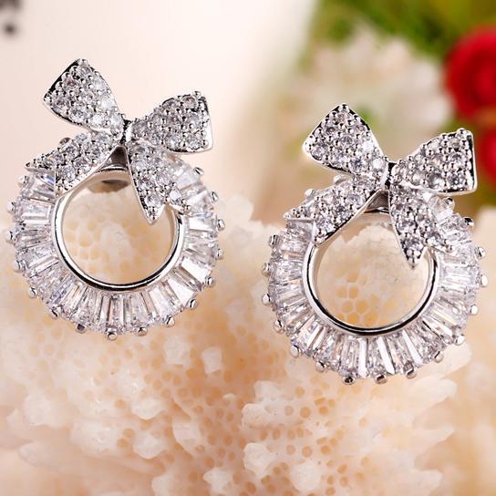 Pair of diamond earrings with bow design on a textured surface