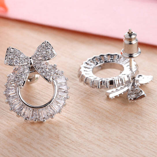 Silver earrings with bow and round design on a wooden surface