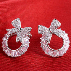 Silver earrings with bow design on a red background