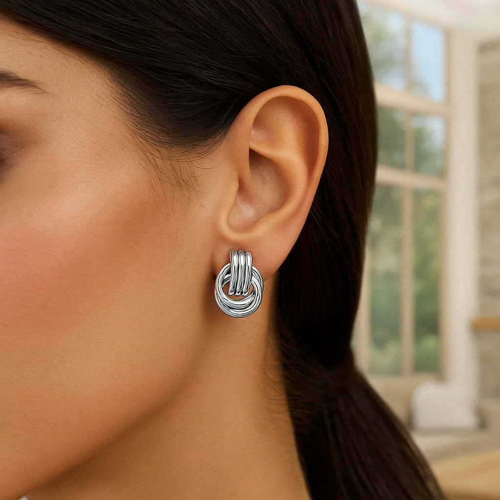 Close-up of a woman wearing a silver knot earring with a blurred background