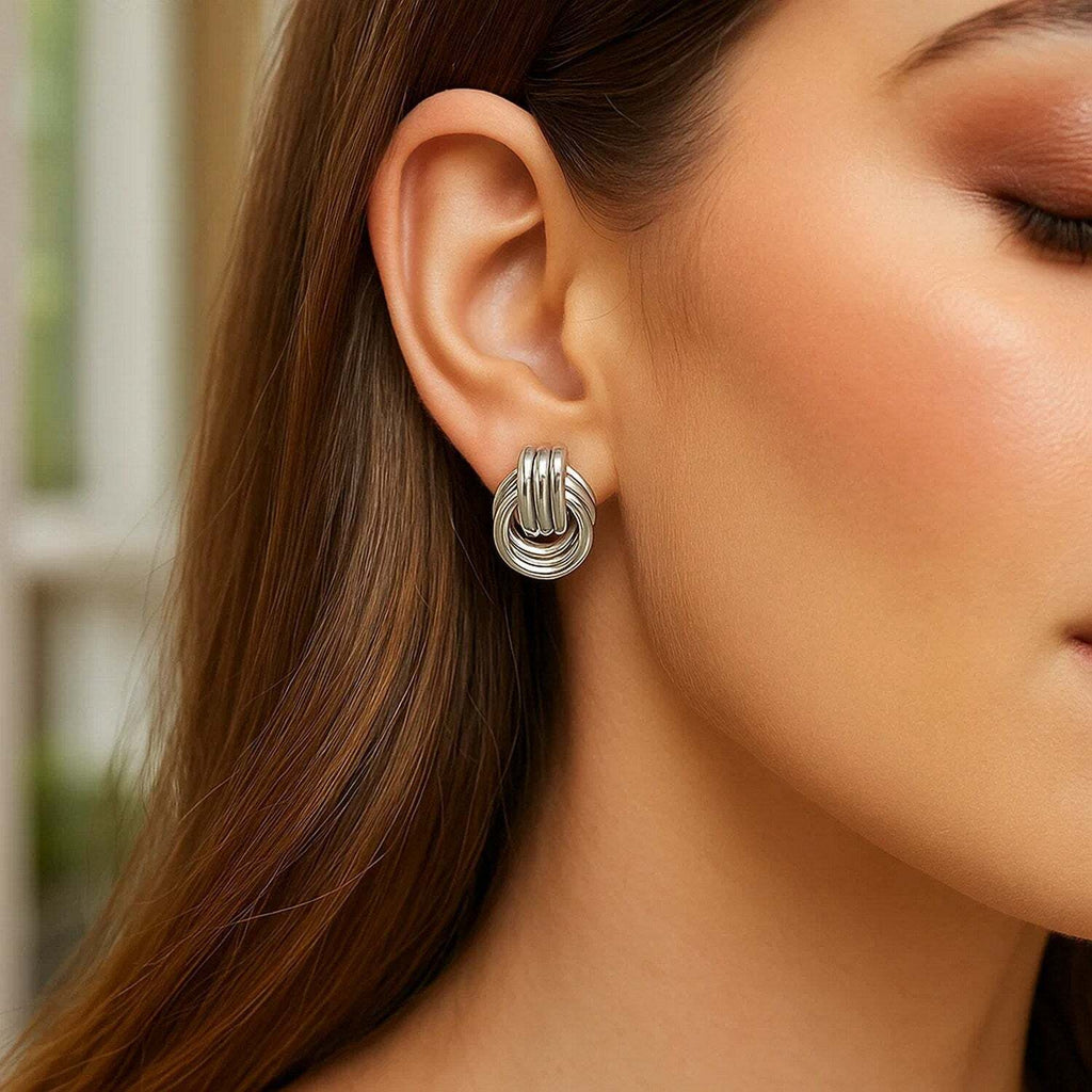 Close-up of a woman wearing a silver knot earring with a blurred background