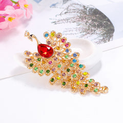 Colorful gemstone brooch with a red gem on a white surface with flowers in the background