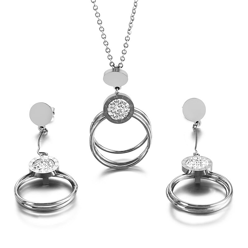 Silver jewelry set with circular designs and clear stones on a white background