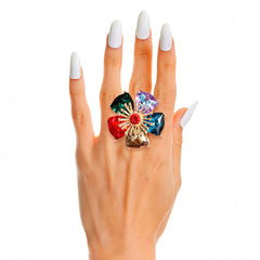Multicolored gemstone ring on a hand with white nail polish against a white background