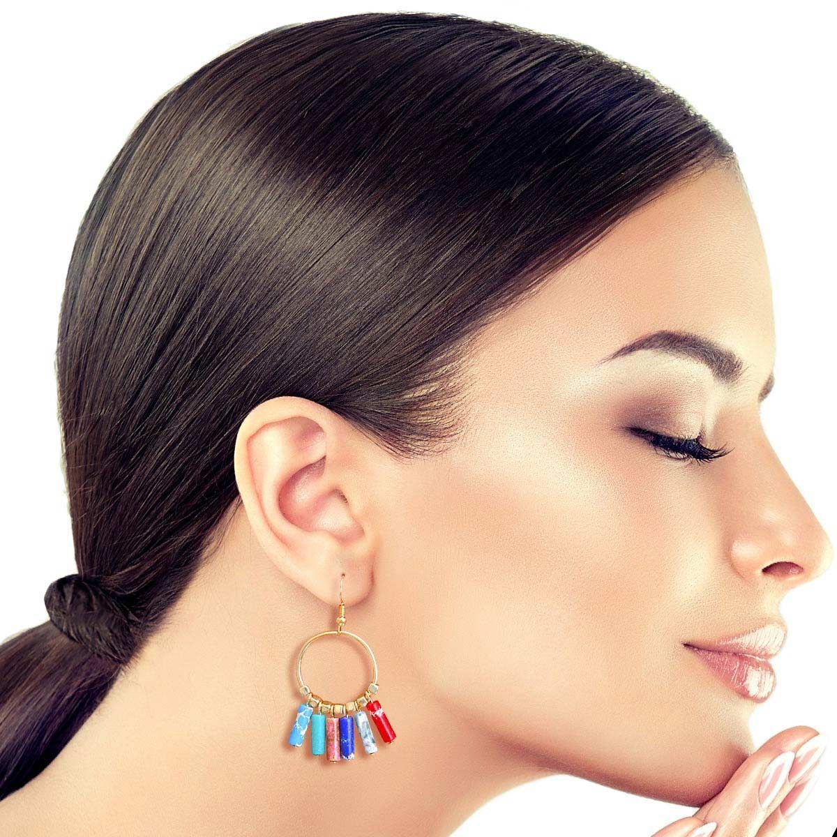 Close-up of a woman wearing colorful hoop earrings with a neutral background