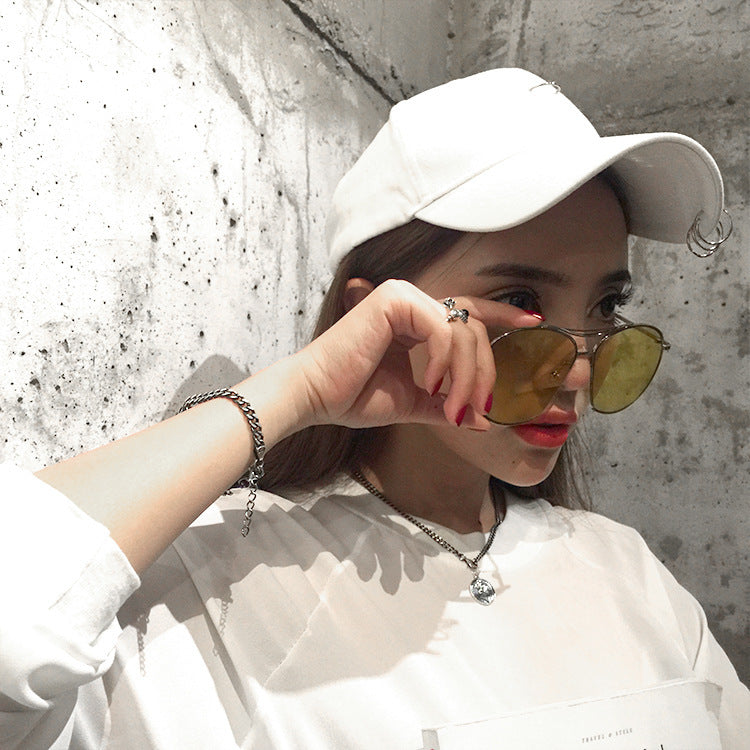 Person wearing a white cap and sunglasses with a neutral background