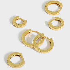 Set of gold hoop earrings on a light gray background