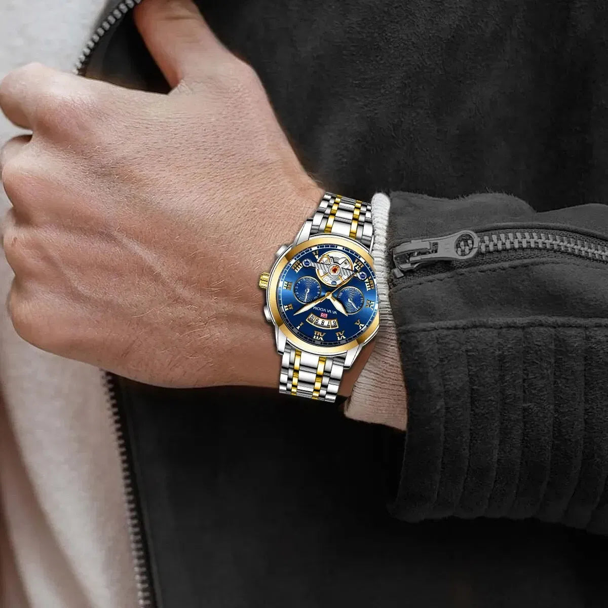 Hand wearing a silver and gold watch with a blue face, against a dark background.
