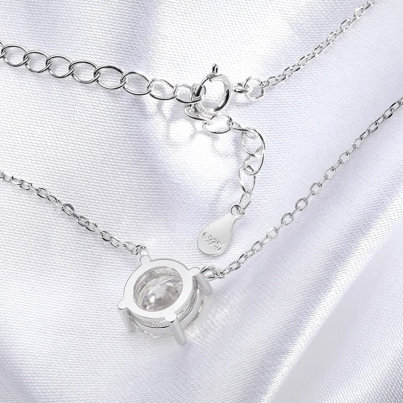 Silver necklace with a clear gemstone pendant on a white fabric background