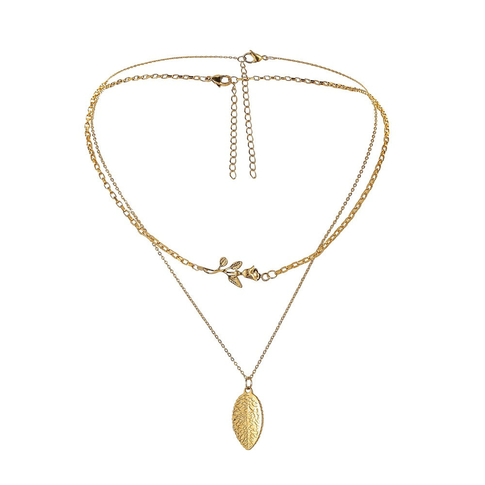 Gold necklace with leaf pendant on a white background